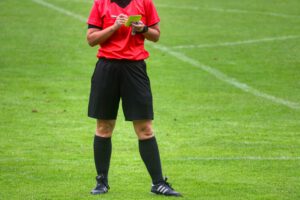 Scheidsrechter bij een voetbalwedstrijd die een kaart uitschrijft