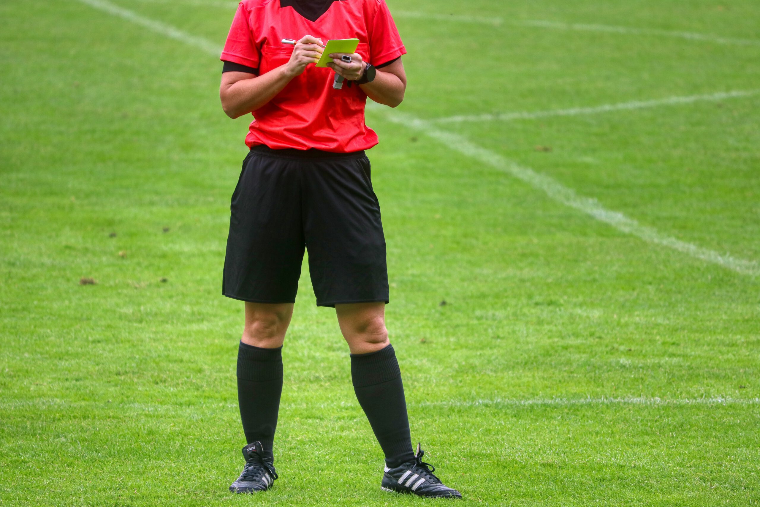 Scheidsrechter bij een voetbalwedstrijd die een kaart uitschrijft