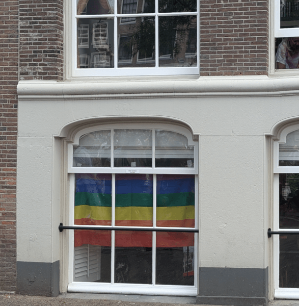 Omgekeerde regenboogvlag achter een kelderraam
